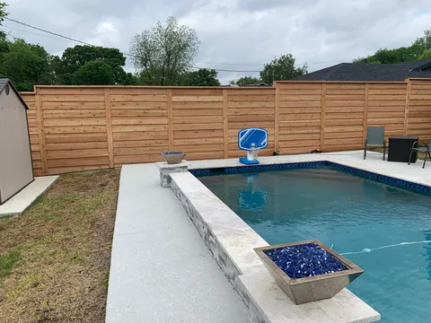 A modern horizontal wood fence providing privacy for a backyard swimming pool and patio area.