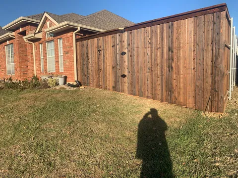 A stained wood privacy fence featuring a wide double gate for yard access.